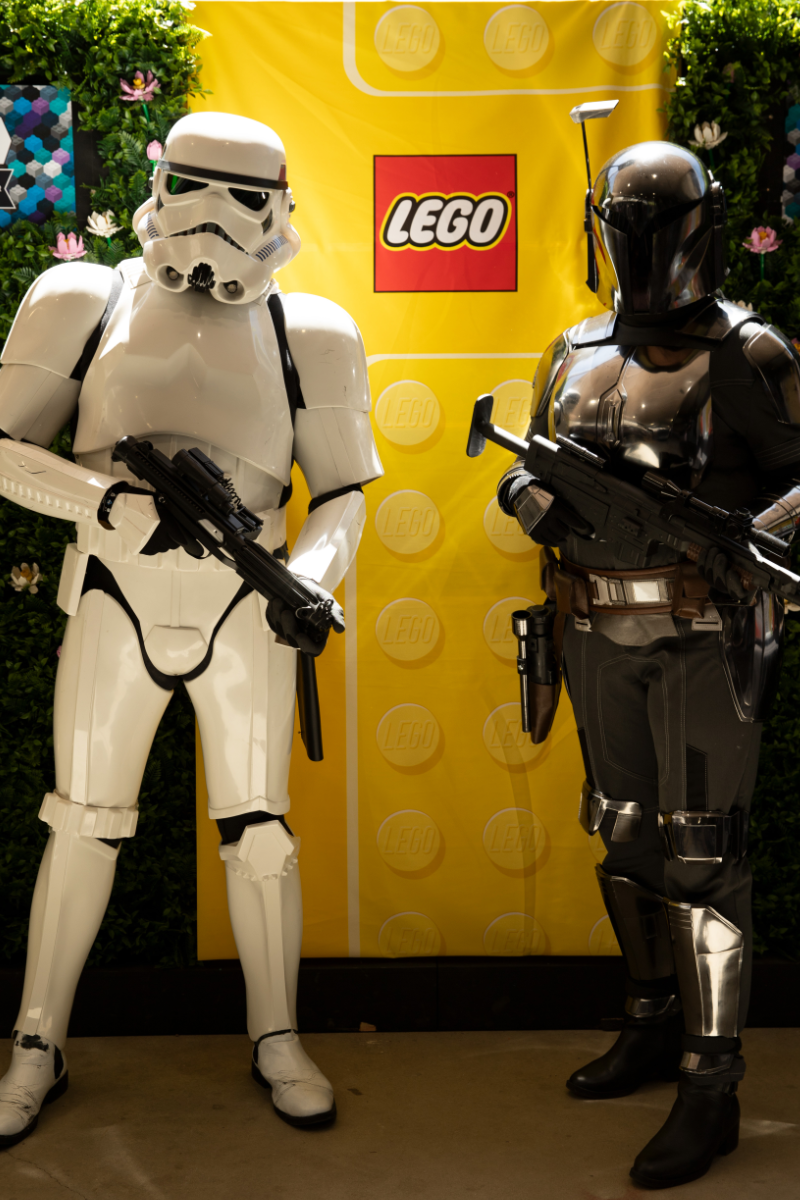 A Storm Trooper from the 501st, and a Mandalorian from the Sandhawk Clan posing for a photo in front of a LEGO banner